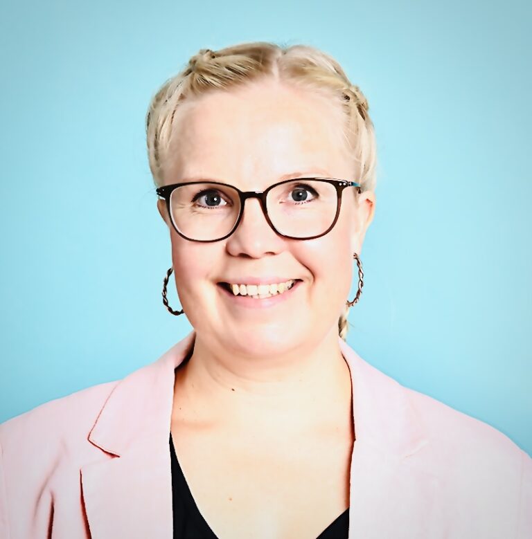 Vaaleahiuksinen nainen hymyilee kameralle